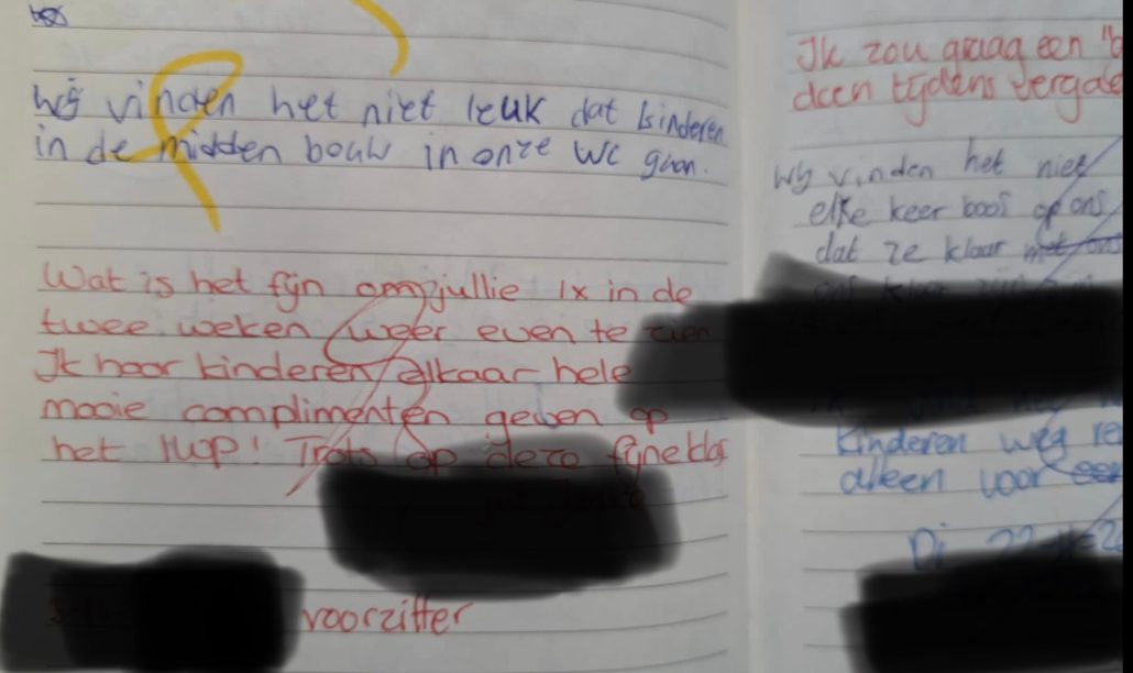 In een schrift is met blauwe en met rode pen geschreven. Door de blauwe tekst staat een gele krul.